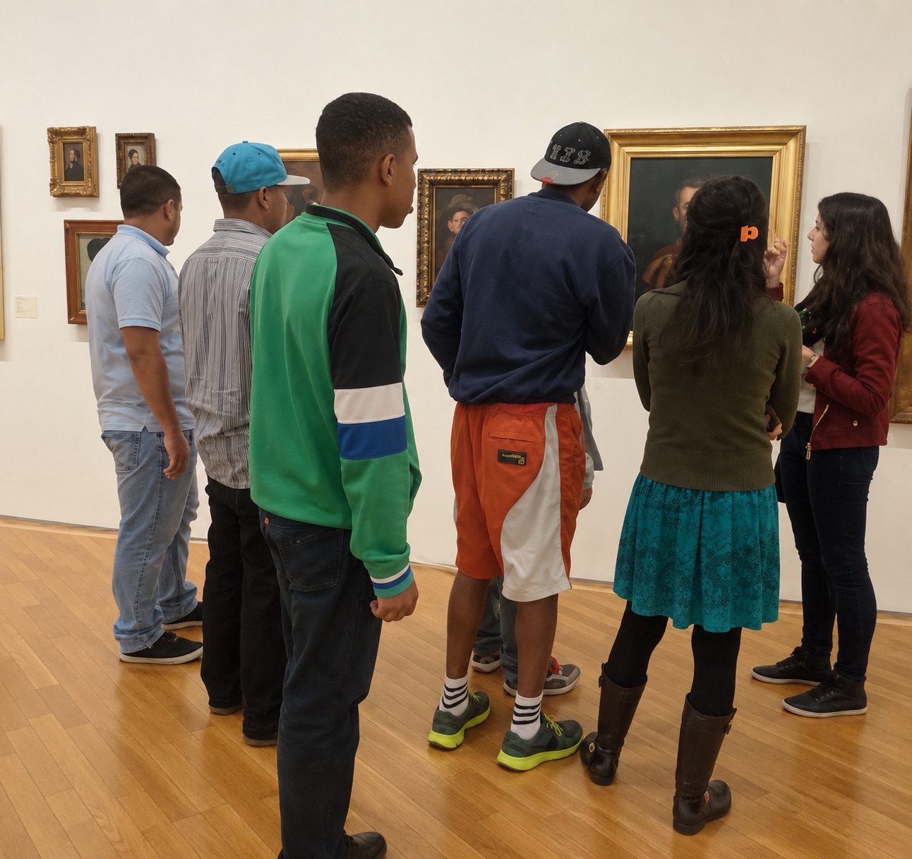 Participantes do CAPS com a educadora da Pinacoteca diante de retratos na galeria